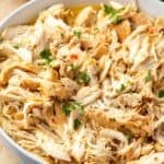 Shredded slow cooker Italian chicken in a large white bowl.