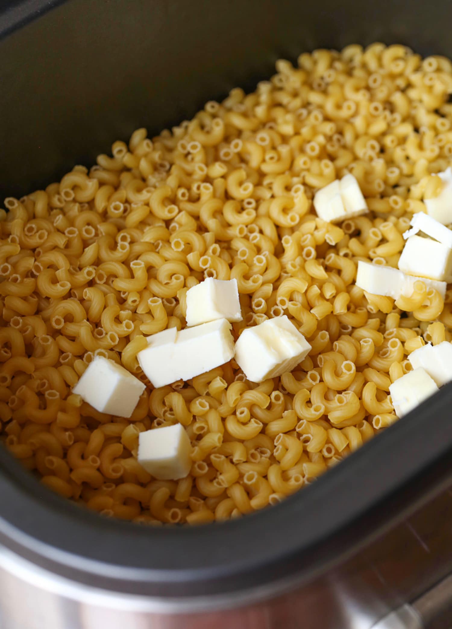 Cubes of butter on top of uncooked pasta in a Crock Pot