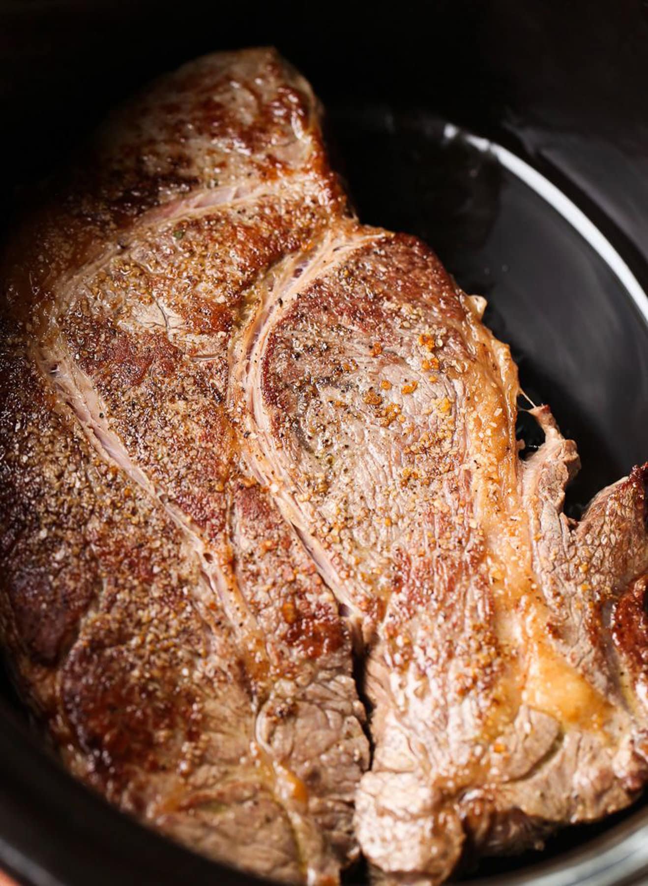 Seared chuck roast in the bowl of a slow cooker.