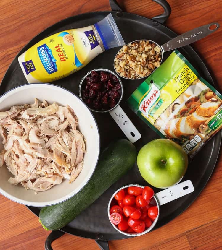 Shredded chicken, an apple, a zucchini, craisins and the rest of the salad ingredients on a black serving platter