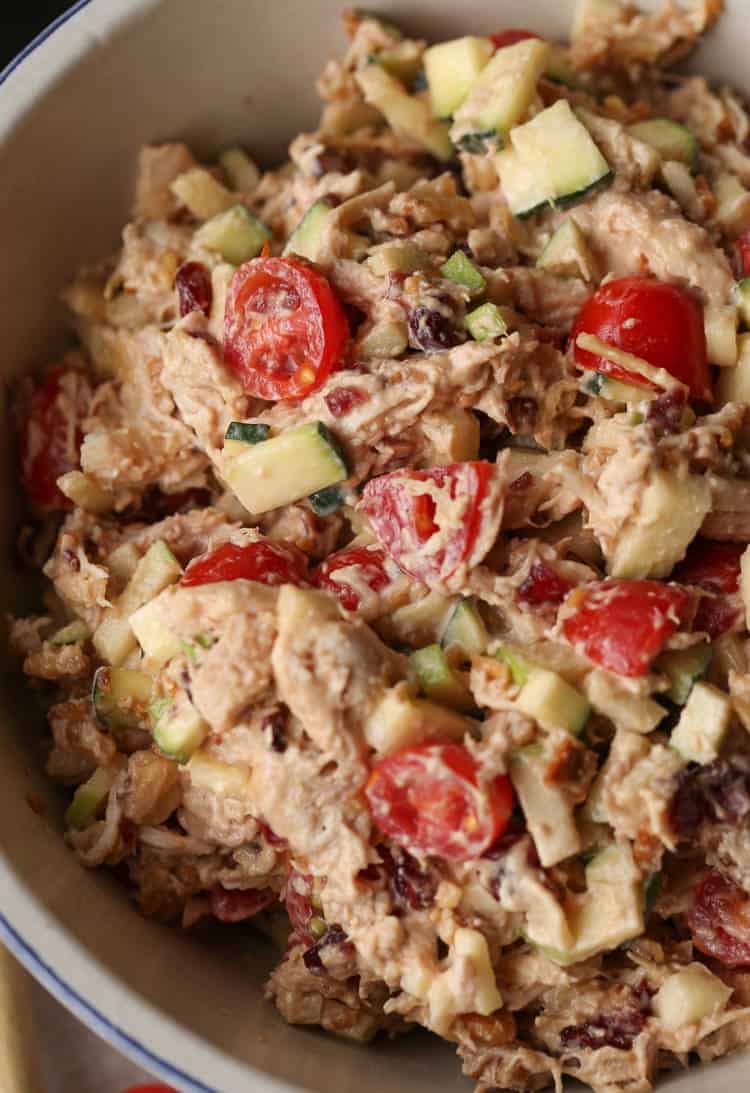 A close-up shot of a leftover chicken salad inside of a taupe bowl with a blue rim