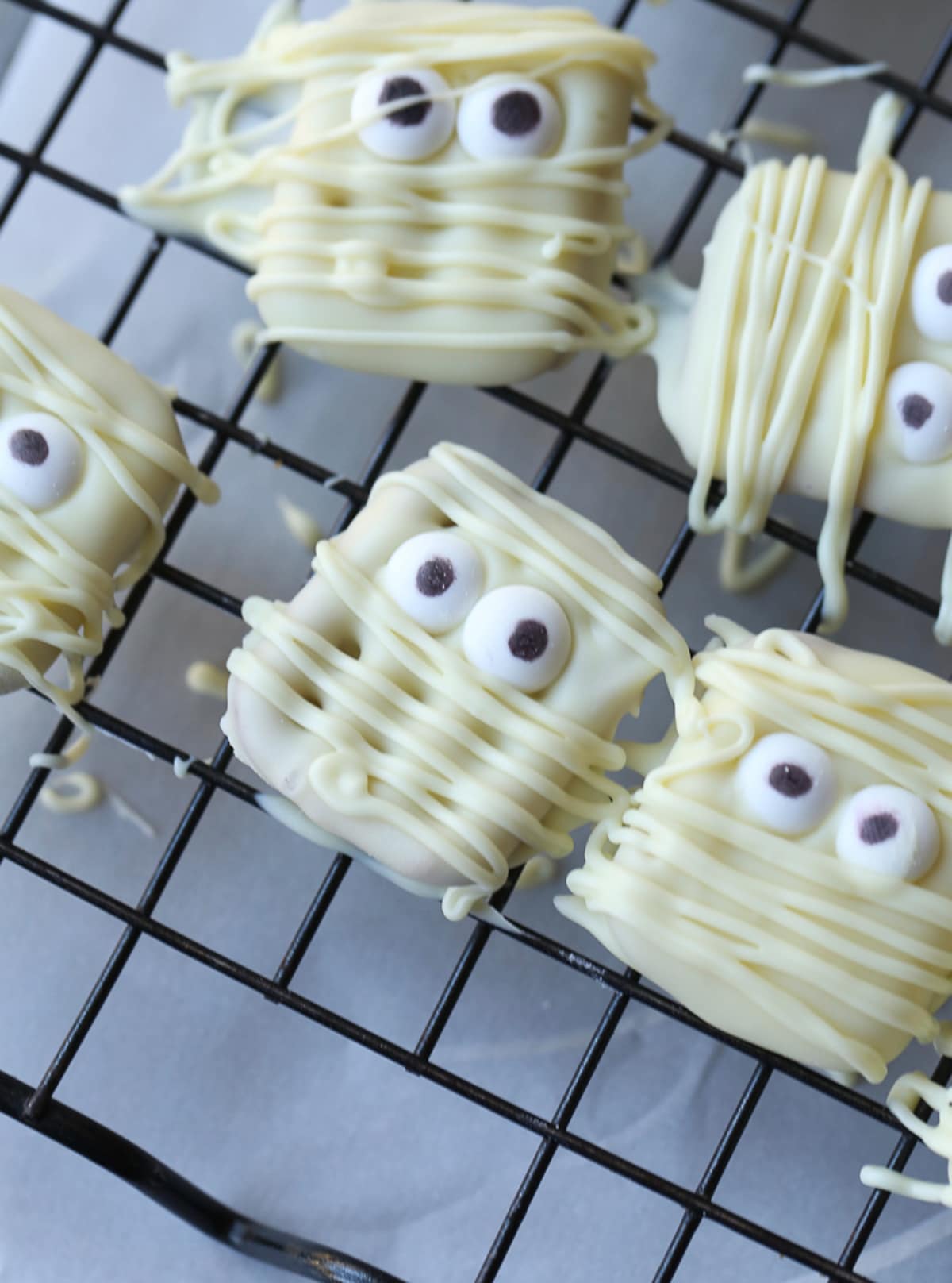 Square white chocolate pretzels with candy eyes and white chocolate drizzles made to look like mummies.