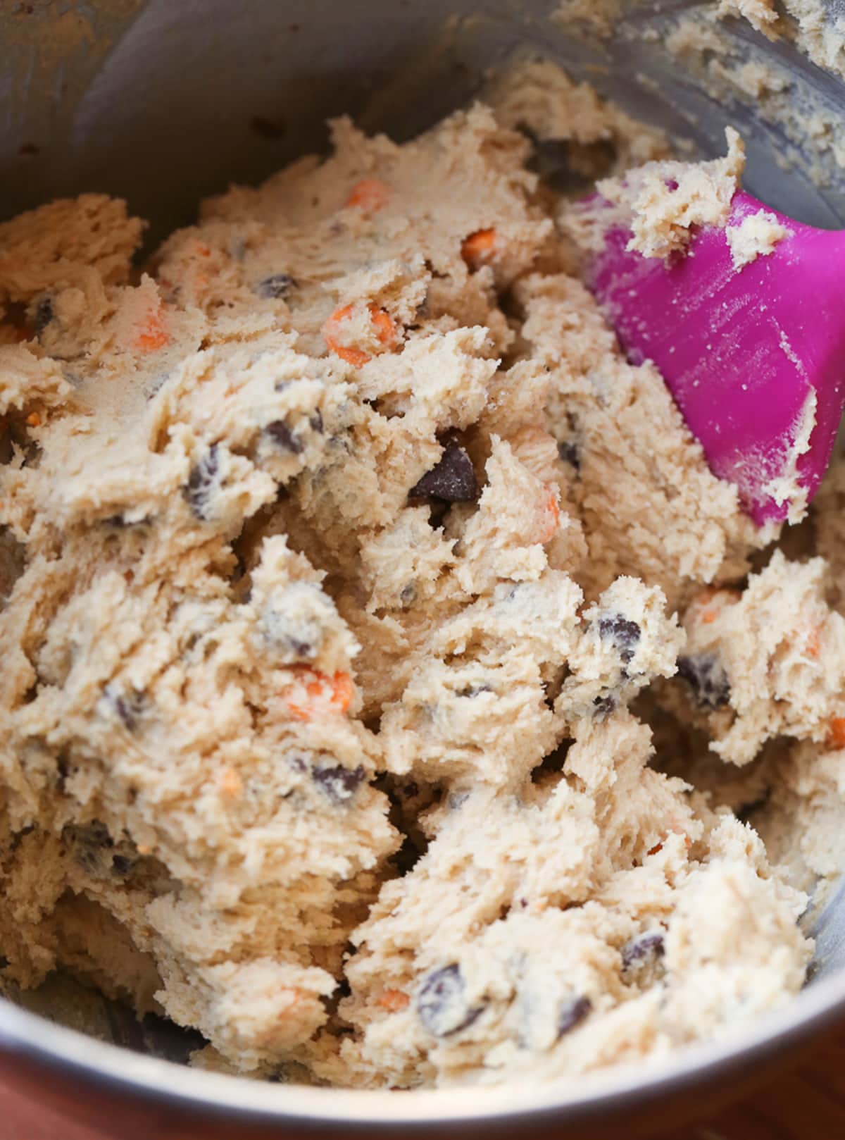 Cookie dough in a mixing bowl with a pink spatula