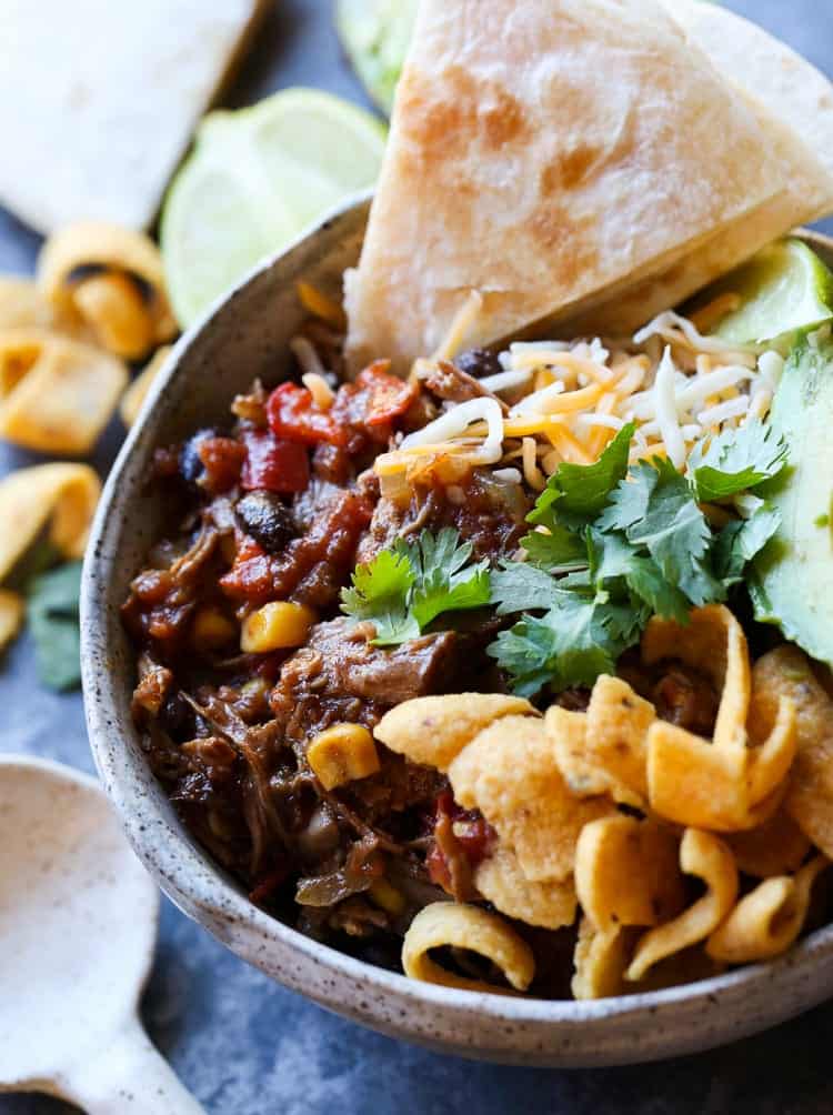 A bowl of taco truck chili with fritos and pita