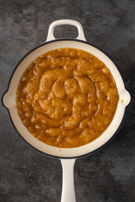 Caramel sauce boiling in a cast iron skillet.