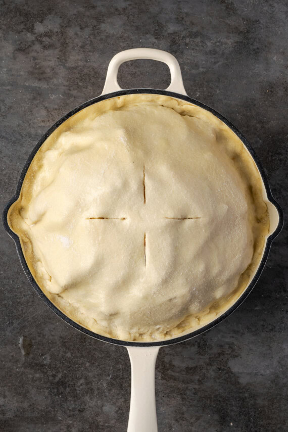 The second pie crust placed over the assembled apple pie in a skillet.