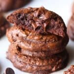Three Gooey Chocolate Truffle Cookies Stacked on a White Cutting Board