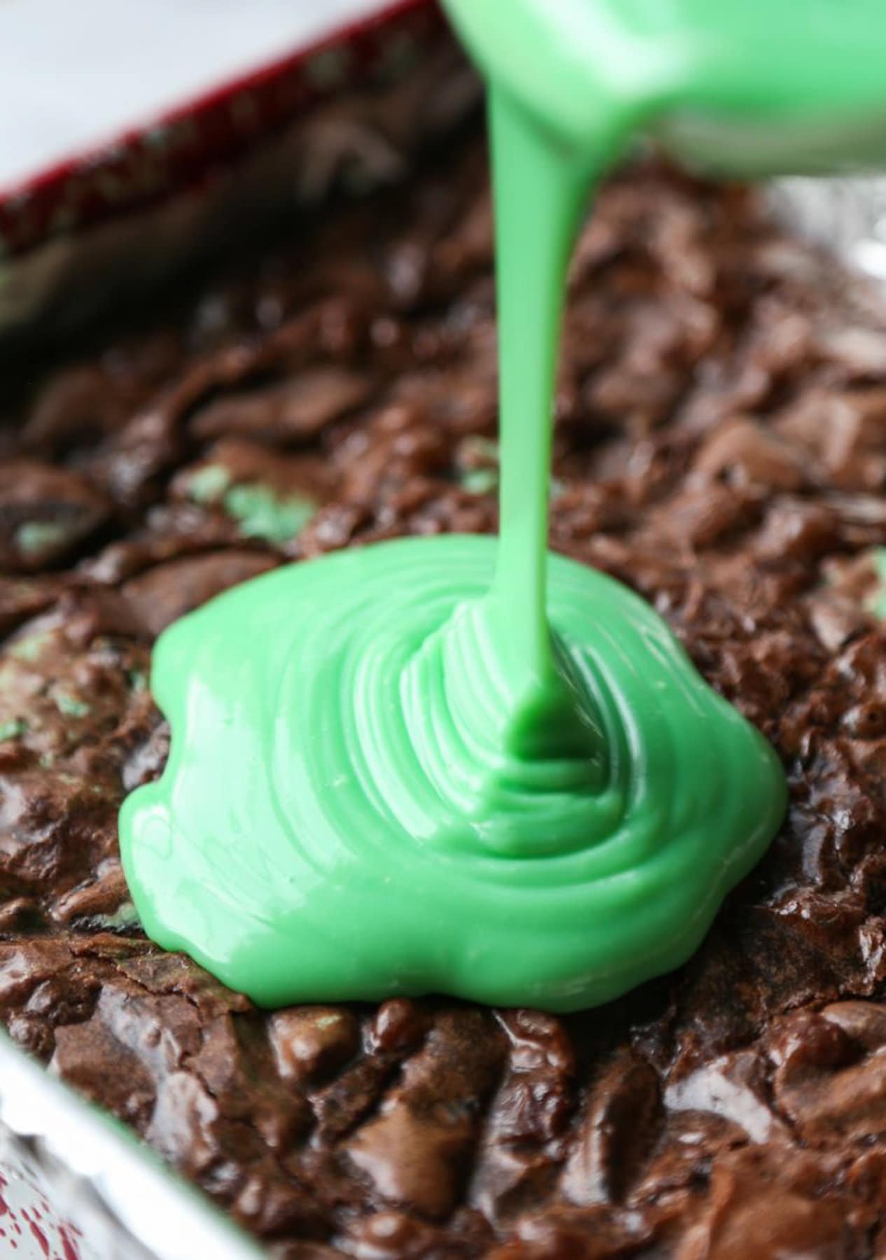 pouring green mix on to cooked brownies 