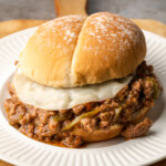 A Crock Pot Philly Cheesesteak Sloppy Joes sandwich on a white plate.