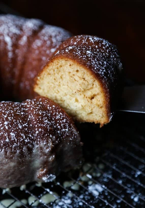 A slice is removed from an eggnog butter cake dusted with powdered sugar.