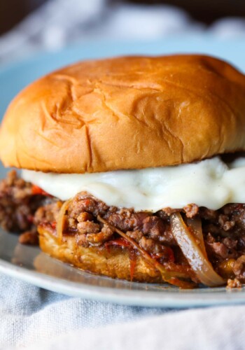 A crock pot philly cheesesteak sloppy joe on a white plate over a kitchen towel