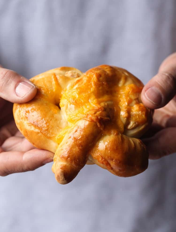 Hands holding a homemade cheesy pretzel.