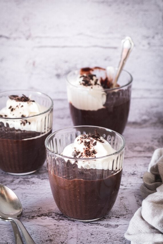 Three bowls of easy chocolate pudding with whipped cream.