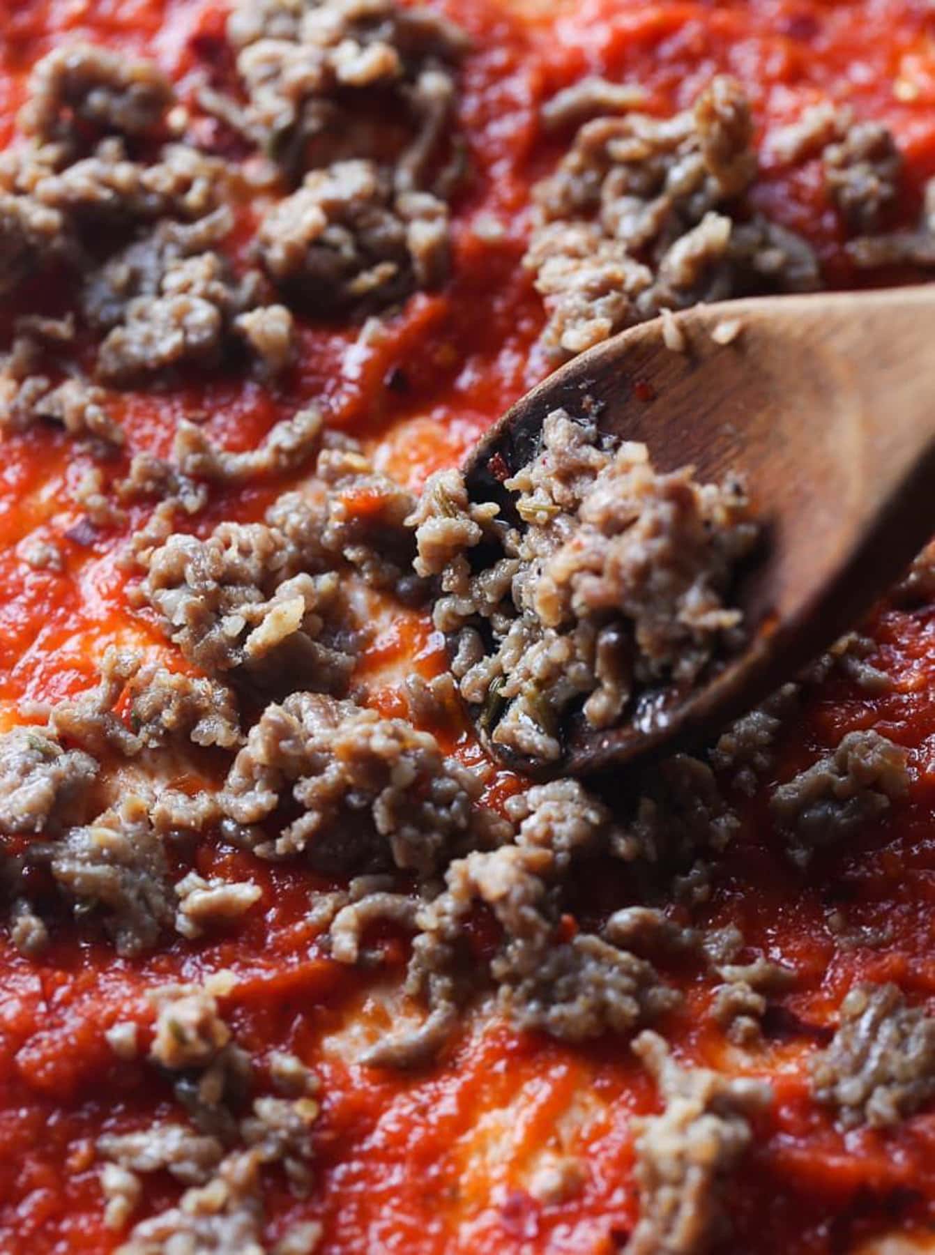 Sausage spread onto pizza sauce