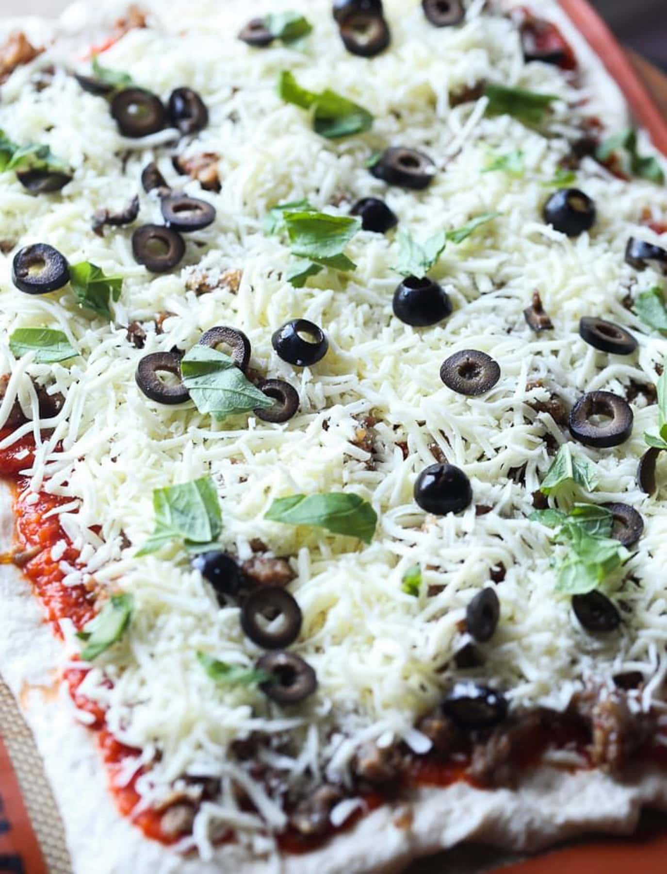 olives and basil spread on pizza