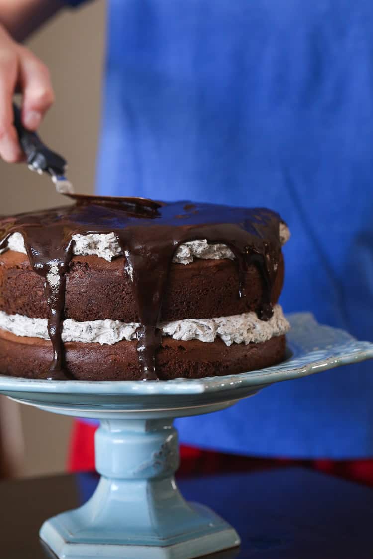 Chocolate Ganache Being Spread Over a Chocolate Cake Layered with Oreo Frosting