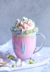 Unicorn Hot Chocolate! It's a creamy hot white chocolate, colored pink, topped with sprinkles, whipped cream, marshmallows, and a blue frosting drizzle!