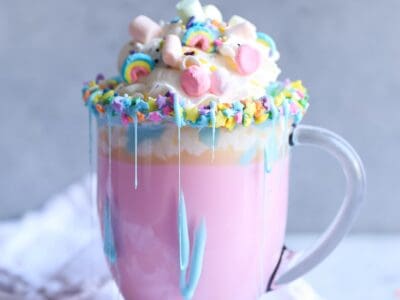 Unicorn Hot Chocolate! It's a creamy hot white chocolate, colored pink, topped with sprinkles, whipped cream, marshmallows, and a blue frosting drizzle!