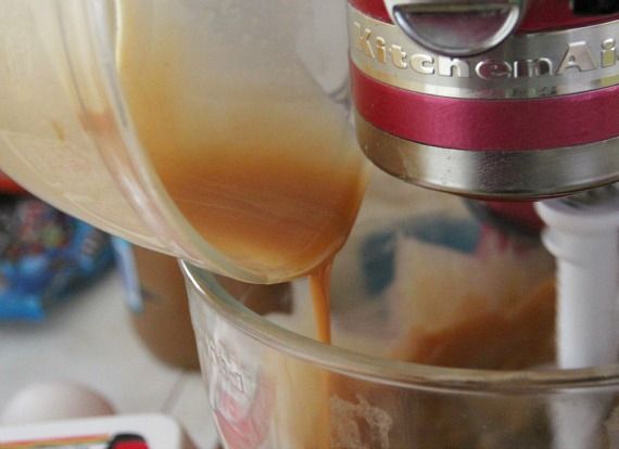 Melted butter and peanut butter being added to a stand mixer bowl