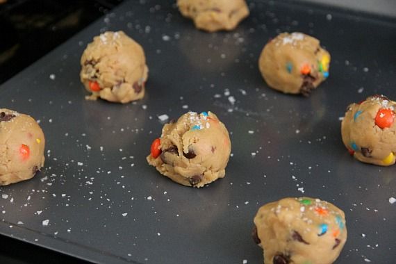 Cookie dough balls with candy pieces on a cookie sheet