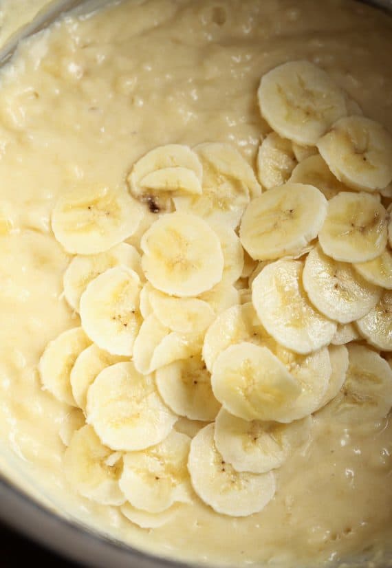 Sliced bananas on top of quick bread batter in a bowl.