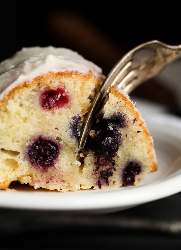 A fork taking a bite from a slice of blueberry bundt cake.