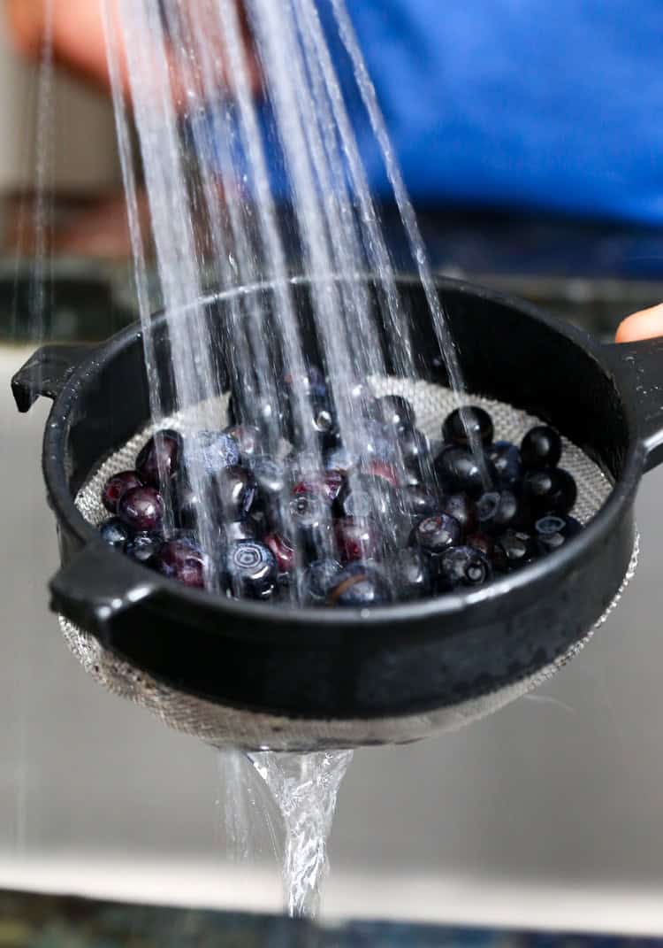 Rinsing blueberries in a colander.