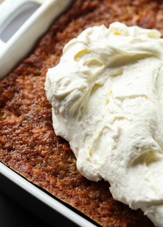 A close up of baked carrot cake topped with a generous smear of cream cheese frosting