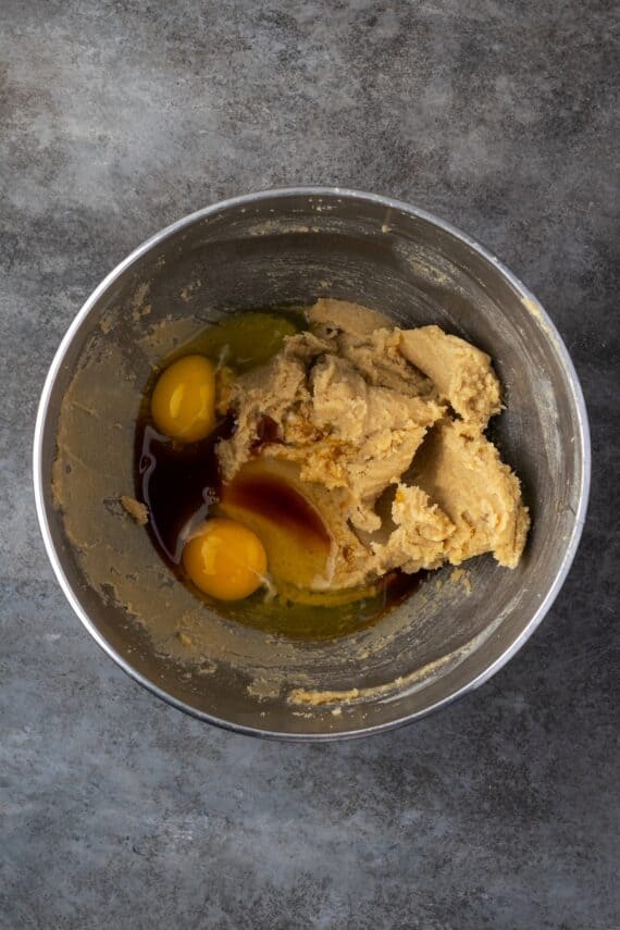 Eggs added to creamed butter and sugar in a mixing bowl.