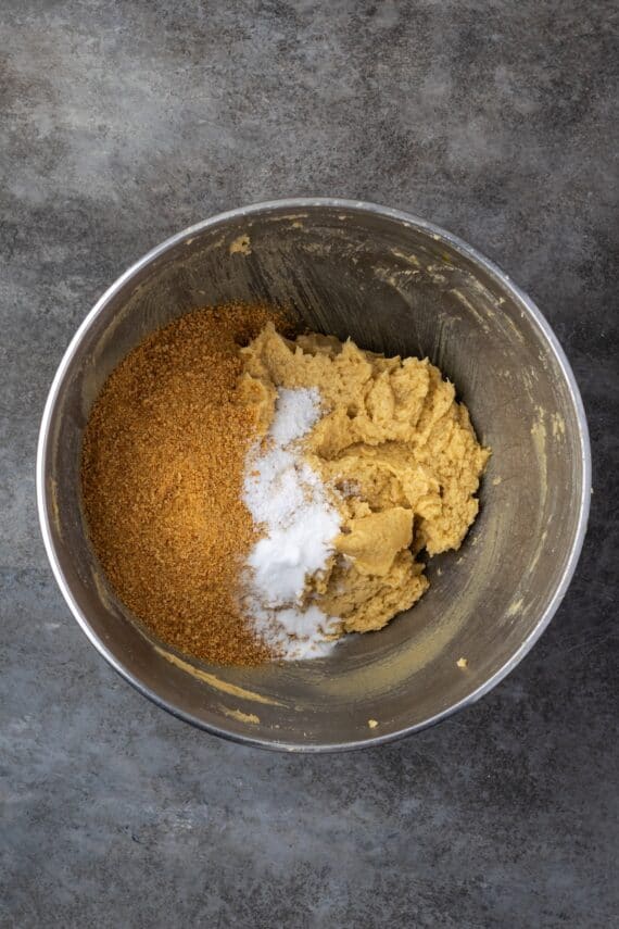 Dry ingredients added to wet cookie dough in a mixing bowl.