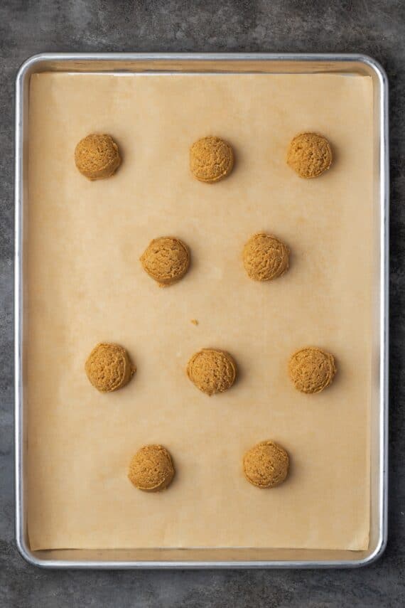 Cookie dough balls spaced apart on a parchment-lined baking sheet.