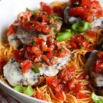 Grilled bruschetta chicken served over a bed of spaghetti.