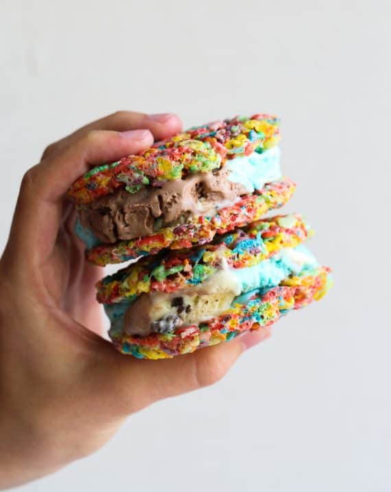A hand holding two Fruity Pebble Ice Cream Sandwiches