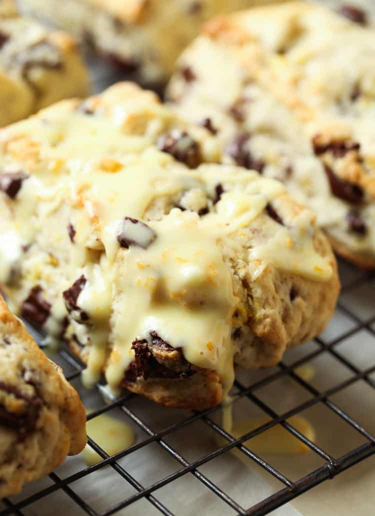 An Orange Chocolate Chunk Scone Dripping with Orange Glaze on a Cooling Rack