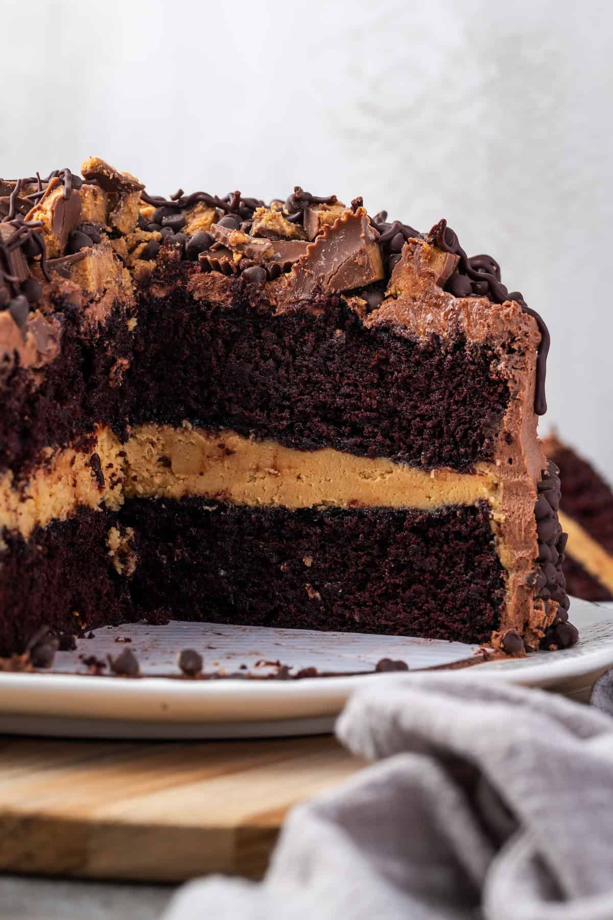 Side view of a Reese's cake with a large slice missing revealing two layers filled with creamy peanut butter frosting.