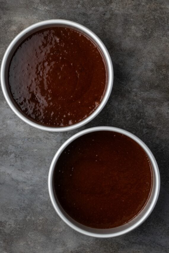 Two round cake pans filled with chocolate cake batter.