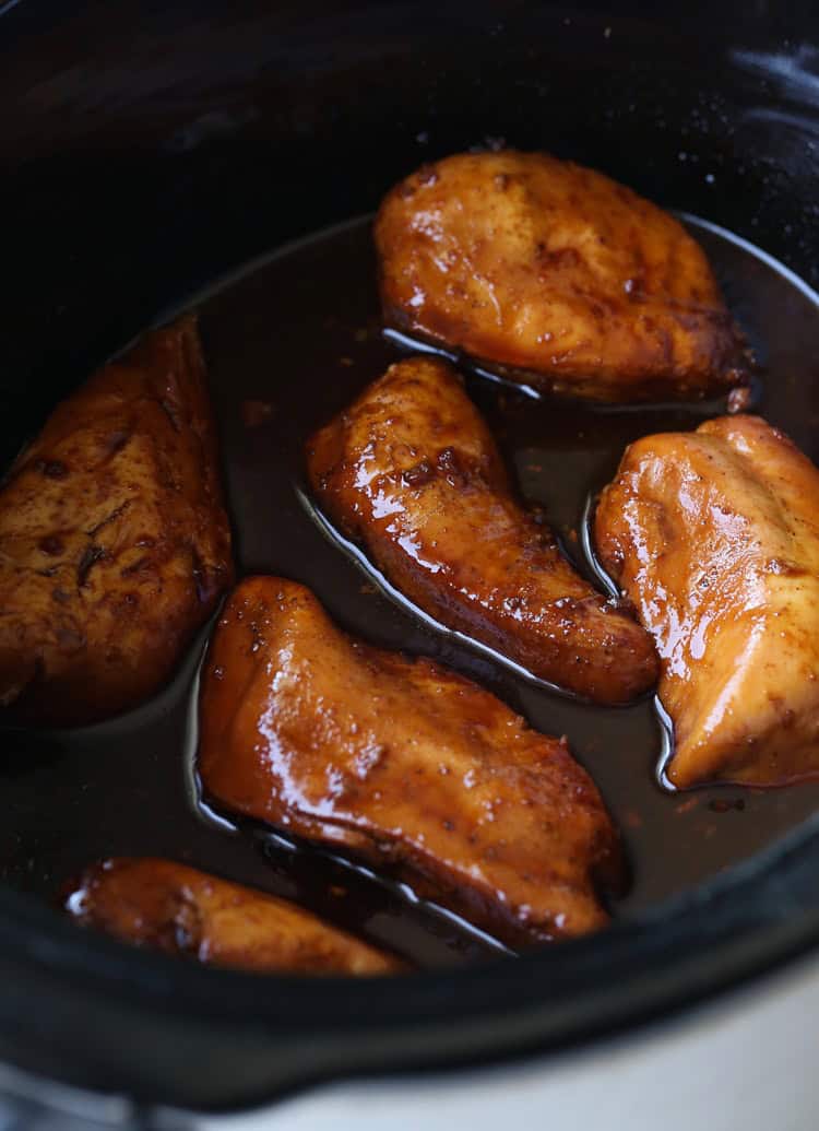 Cooked honey garlic chicken breasts in the bowl of a slow cooker.