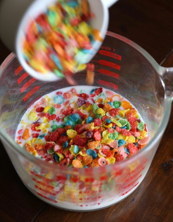Fruity Pebbles Cereal soaking in milk in a glass measuring cup