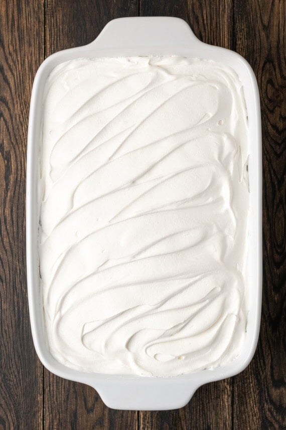 Whipped topping added over top of the chocolate lasagna layers in a ceramic baking dish.