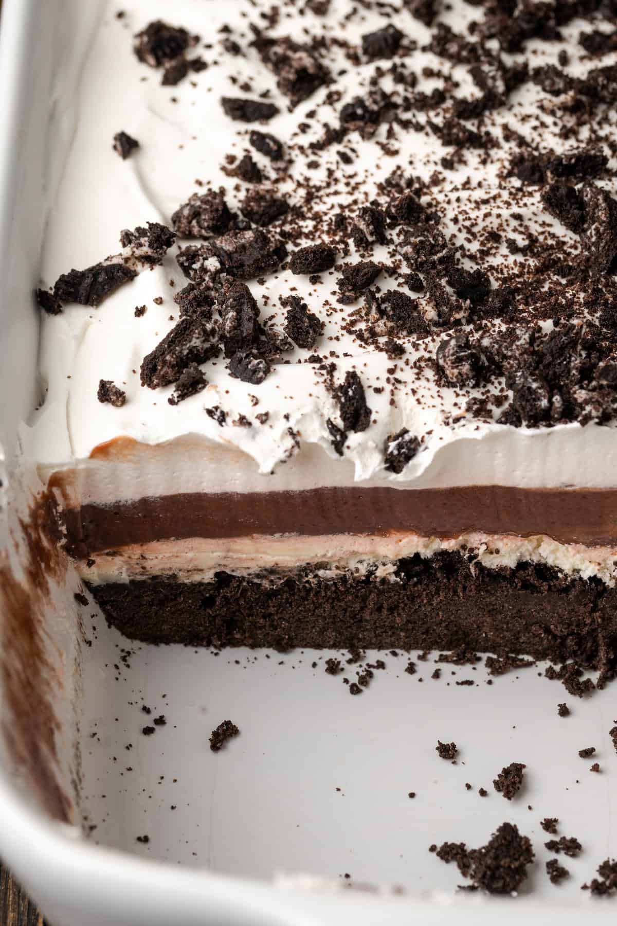 Close up view of chocolate lasagna in a casserole dish with a slice missing from the corner.