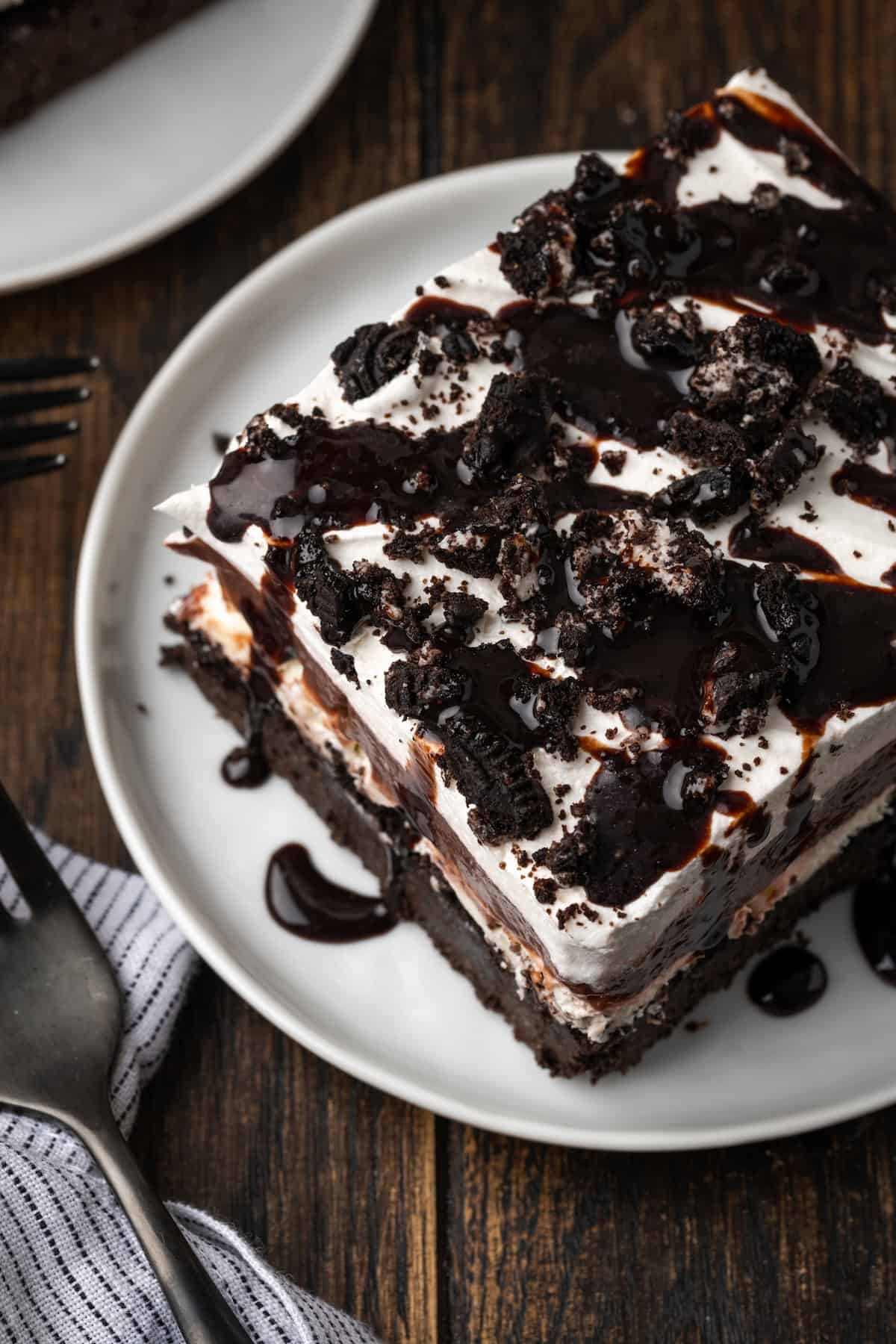 A slice of chocolate lasagna topped with chocolate sauce on a plate.