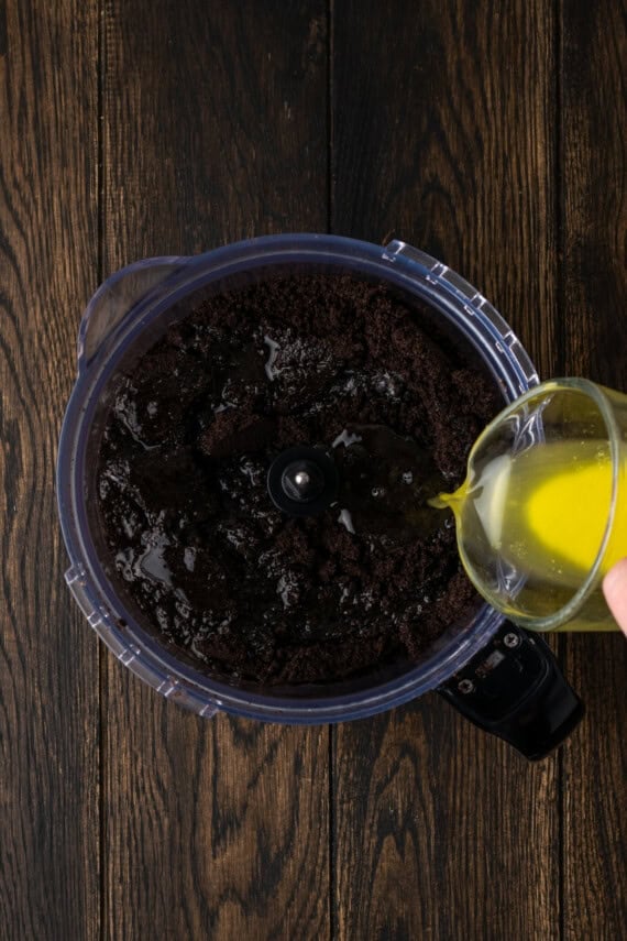 Melted butter poured into a food processor with crushed Oreos.