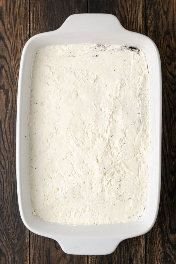 The cream cheese layer added over top of the Oreo crust in a ceramic casserole dish.