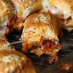 Close up of a chicken parmesan slider surrounded by more sliders in a baking dish.