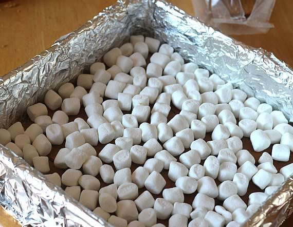 A layer of mini marshmallows on top of graham crackers in a foil-lined baking dish
