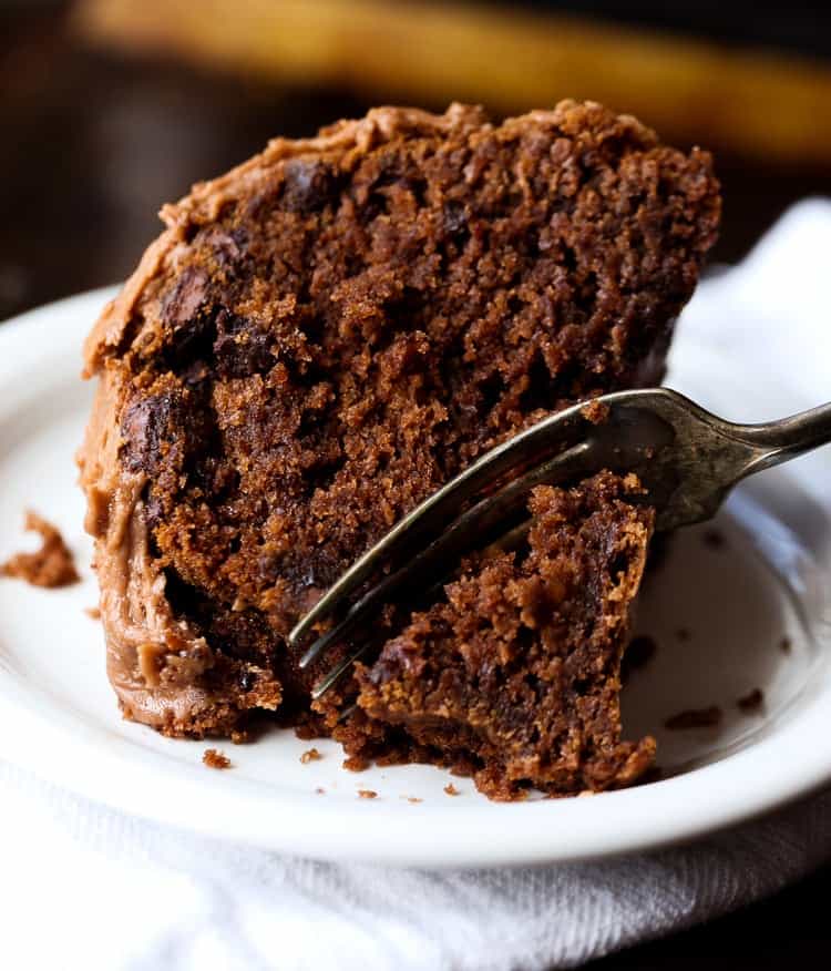 A slice of chocolate cake on a plate with a fork taking a piece out