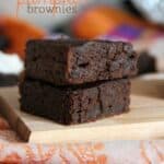 Two pumpkin brownies stacked on a wooden board