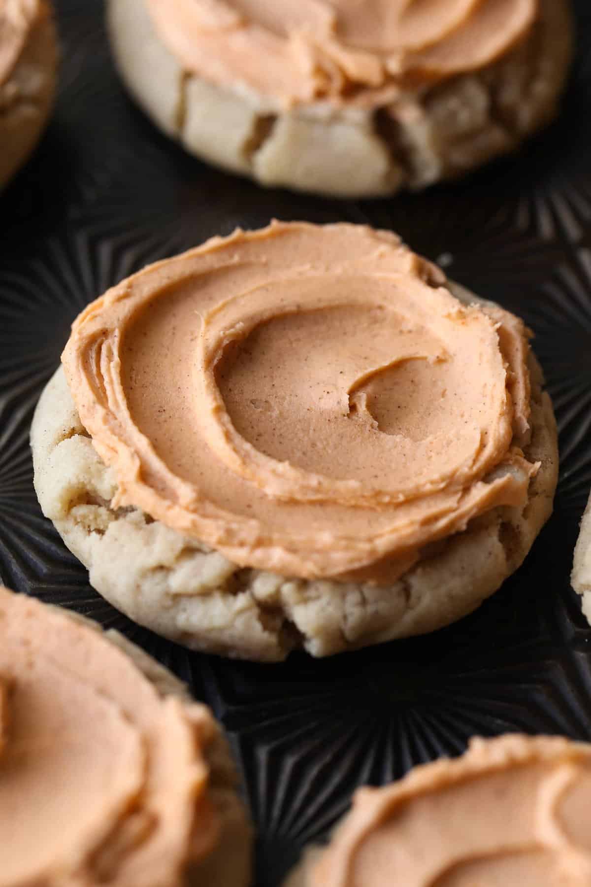 Browned butter frosting covering the top of a pumpkin spice sugar cookie