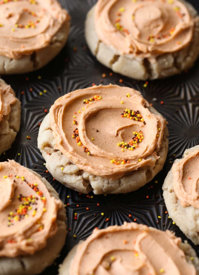 Pumpkin spice sugar cookies on a tray, topped with brown butter frosting and sprinkles
