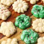 Perfect Spritz Cookies in various shapes and colors arranged on a wooden countertop.